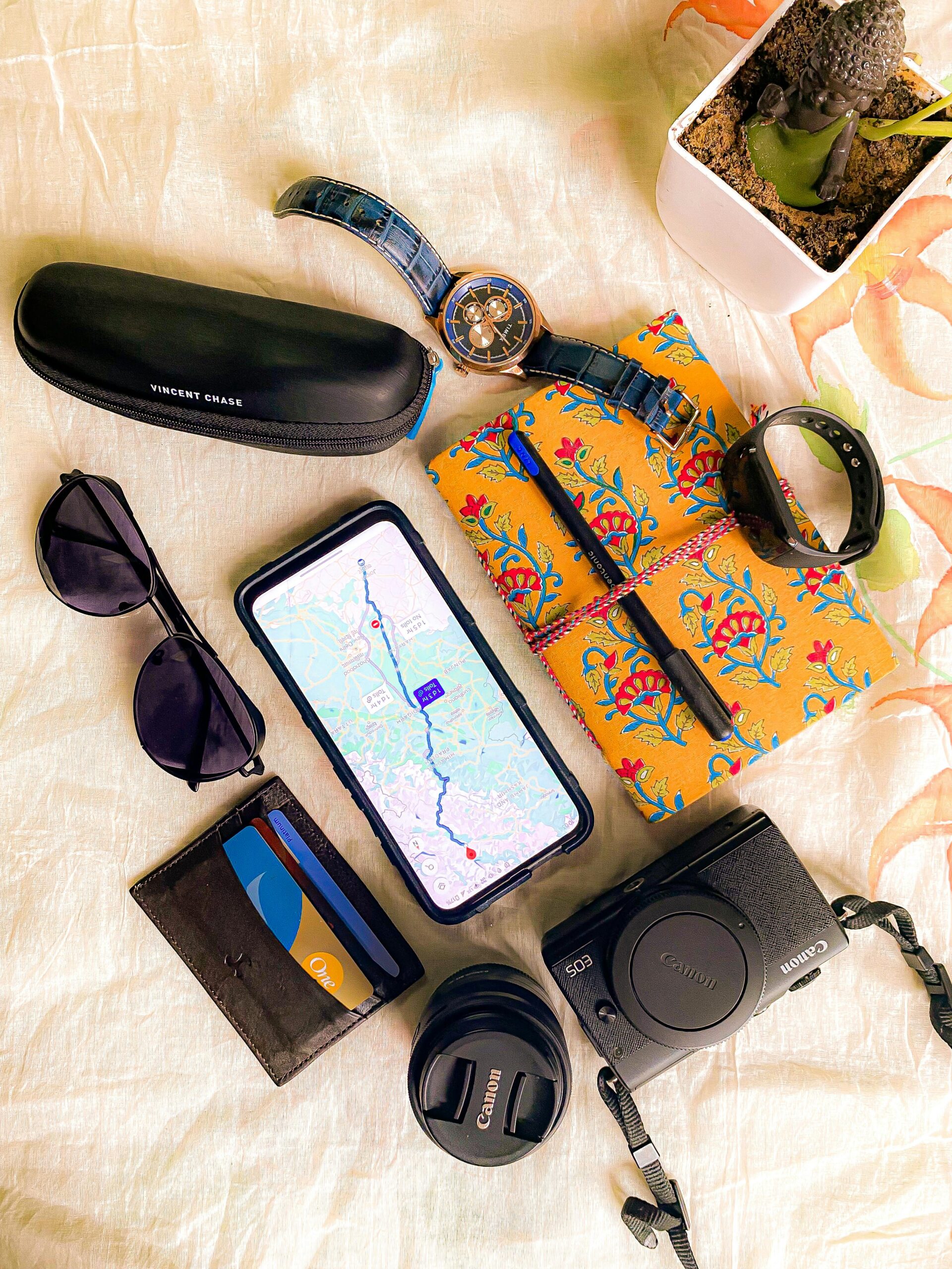 "Flat lay of travel essentials list including backpack, shoes, camera, sunglasses, passport, and map for a perfect travel essential list."