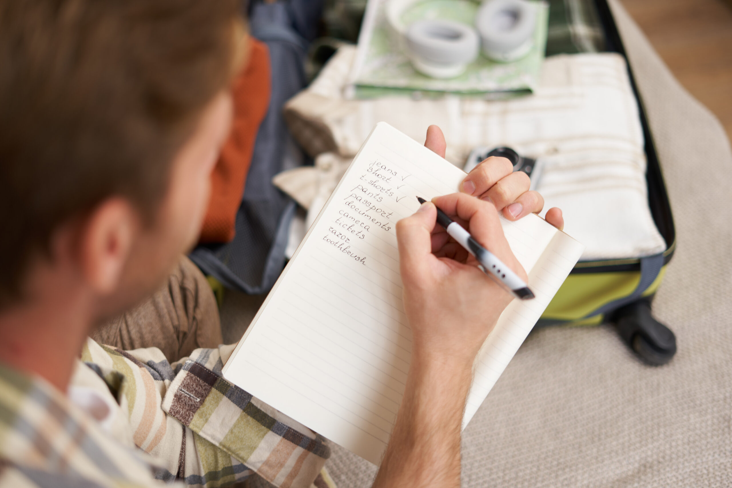 Man checking Road Trip Checklist while packing travel essentials